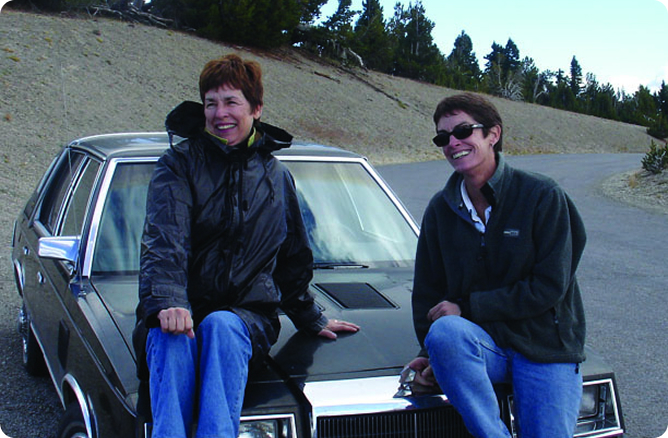 women sitting on a car